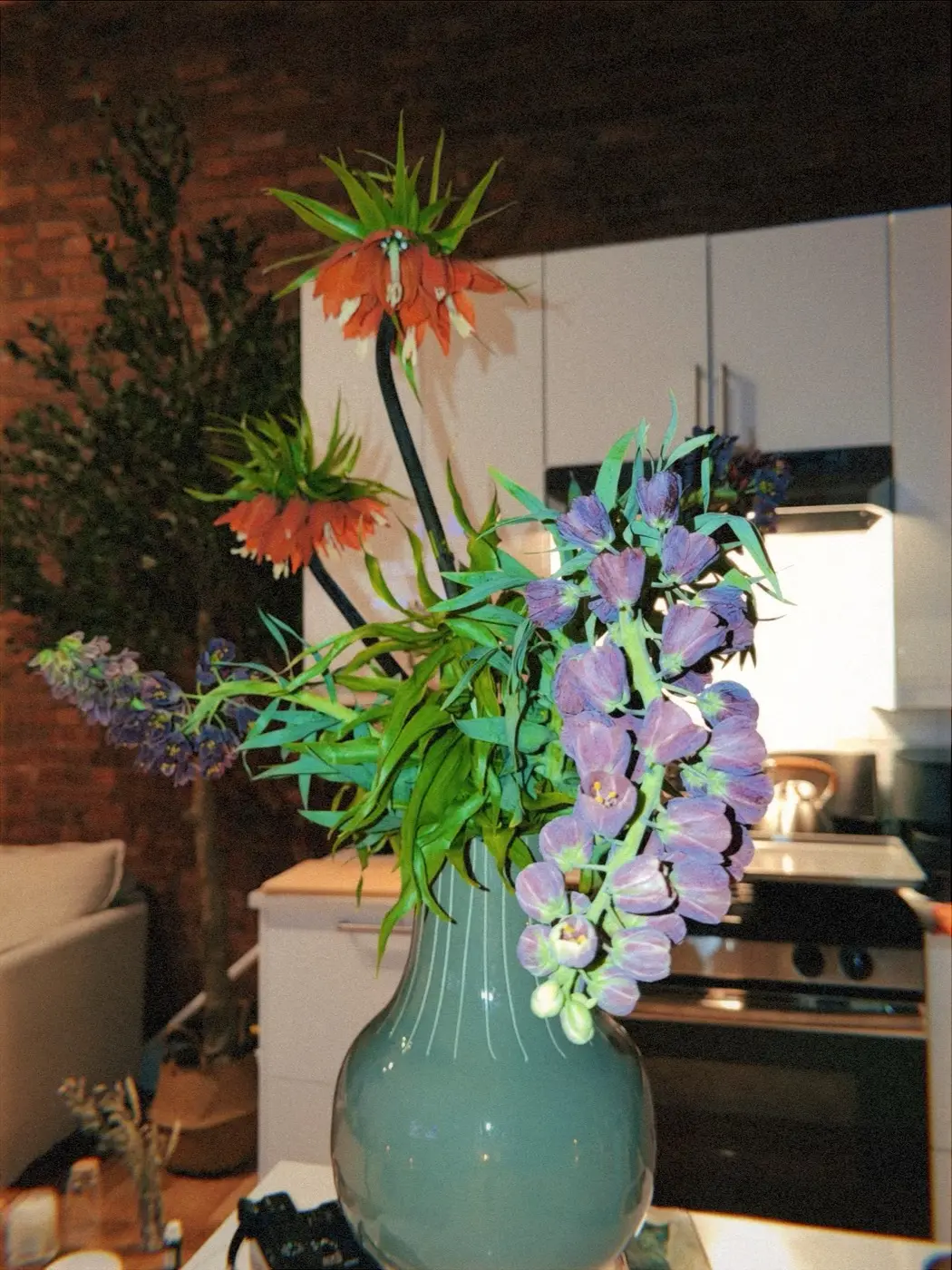 the living room before guests arrive, with an arc lamp, a long table and fresh flowers against exposed brick, before a sound bath in SoHo, New York