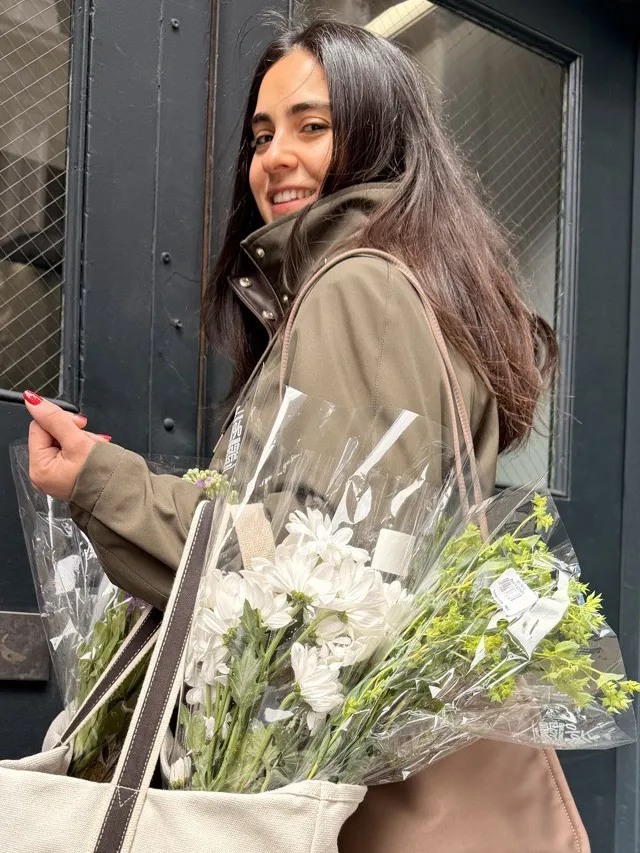 Meltem Cakmak Shuman, founder and host of dear me collective, carrying flowers through SoHo, New York