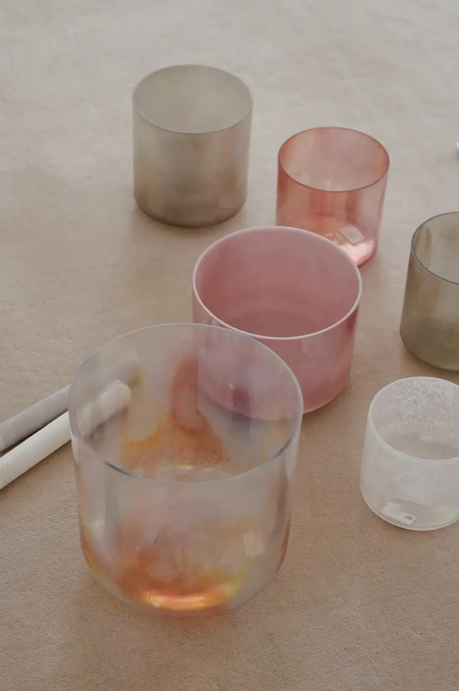 five frosted crystal singing bowls and suede mallets laid out on a pale carpet, before a sound bath in a SoHo living room, New York